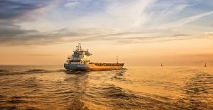Amaizing Sunset. Empty container ship is sailing alonge the waterway during sunset. Small ship, colorfull sky and sea surface, dramatic blue dark sky.