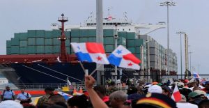 People wave Panama flags as they wait for the Chinese COSCO container vessel named Andronikos to navigate through the Agua Clara locks during the first ceremonial pass through the newly expanded Panama Canal in Agua Clara