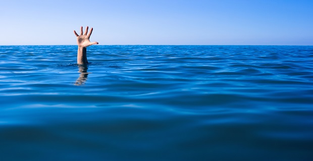 Help needed. Drowning man's hand in sea or ocean.