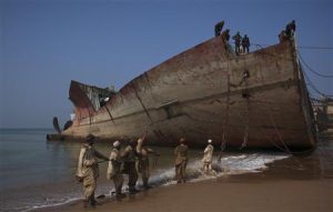 Laborers pull an iron rope before separating a portion of a ship into scrap metal at Gaddani ship breaking yard, about 60 km (37 miles) from Karachi