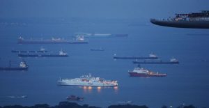 Ships anchor outside the harbour as they wait to berth at a port terminal, near the skydeck of the Marina Bay Sands hotel and casino, in Singapore