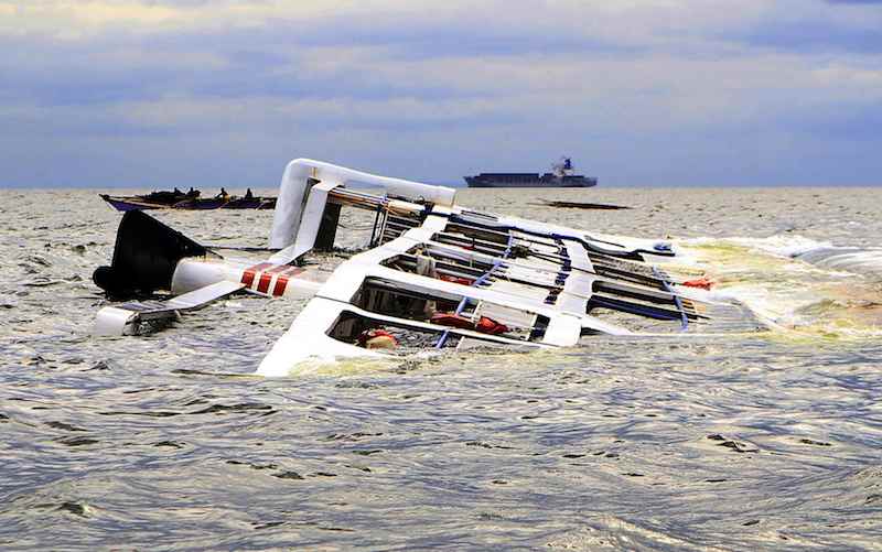 A fishing boat passes the Super Shuttle Ferry 7 which capsized in strong winds and huge waves unleashed by Typhoon Kalmaegi, locally named Luis, in Manila Bay